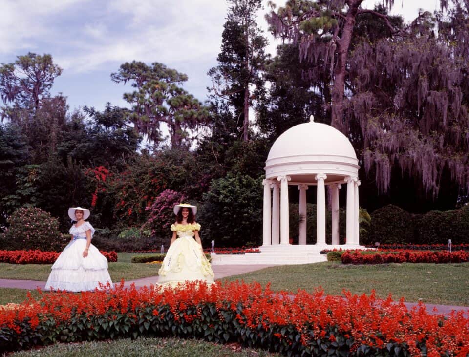 A costumed Southern belle beside the white gazebo at the historic Cypress Gardens in Winter Haven, Florida