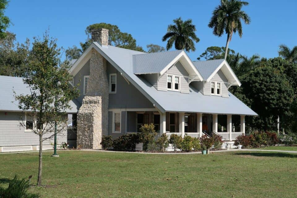 Two-story home with a covered front porch surrounded by mature trees in a suburban neighborhood