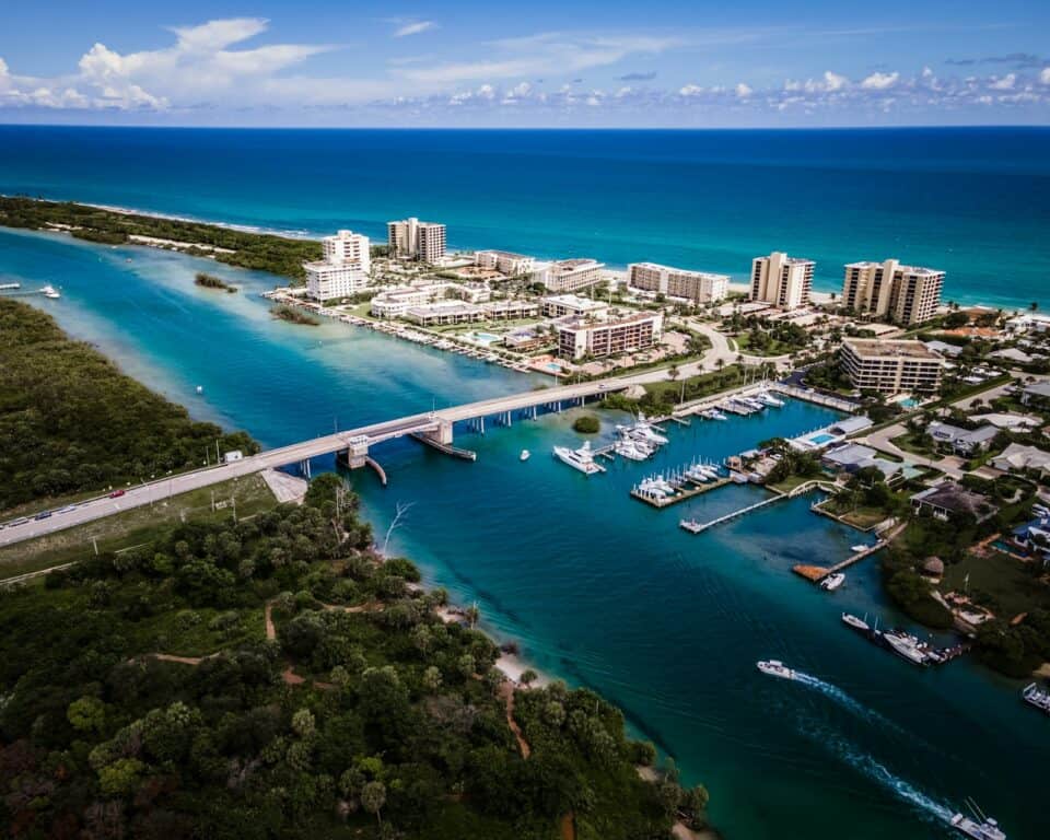 Aerial view of a Florida intracoastal inlet with a bridge, marina and waterfront condominiums
