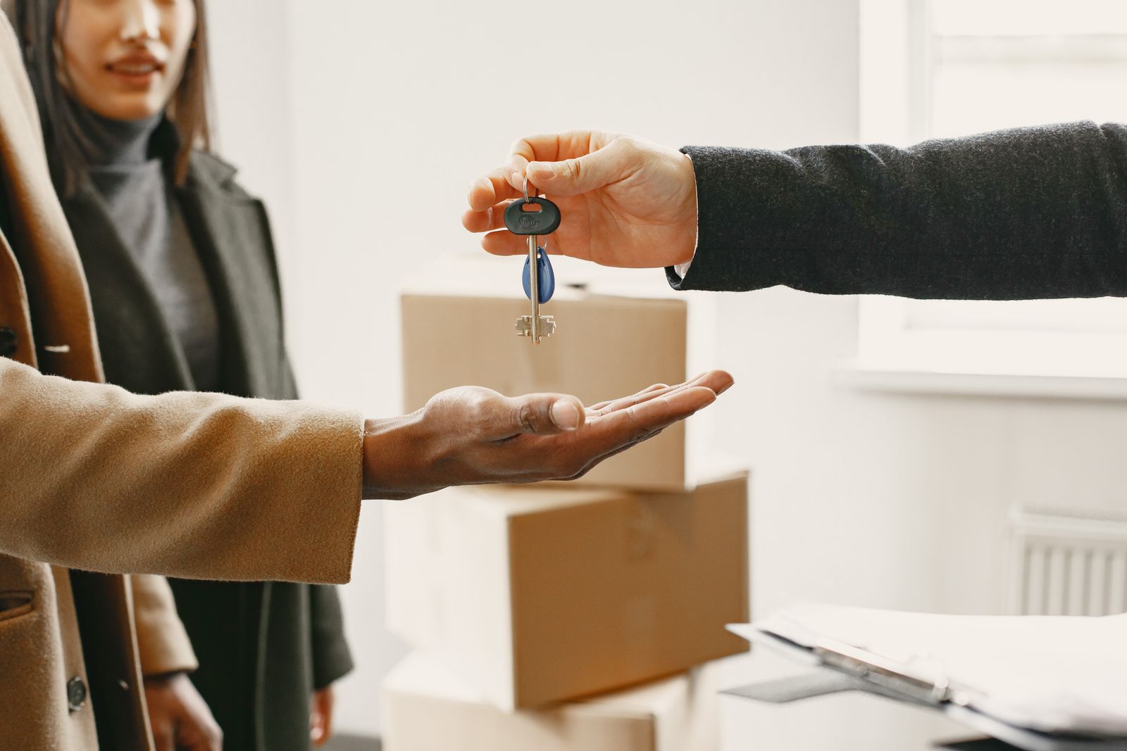A new homeowner receiving the keys to their home, with moving boxes in the background