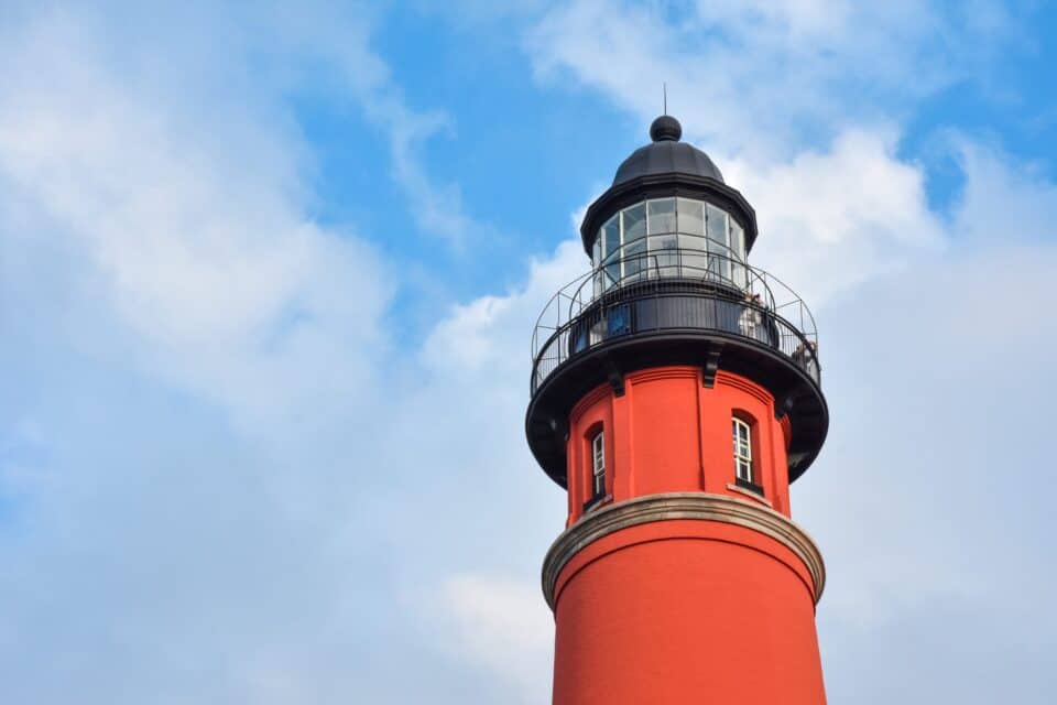 The red Ponce Inlet Lighthouse against a blue sky near New Smyrna Beach, Florida