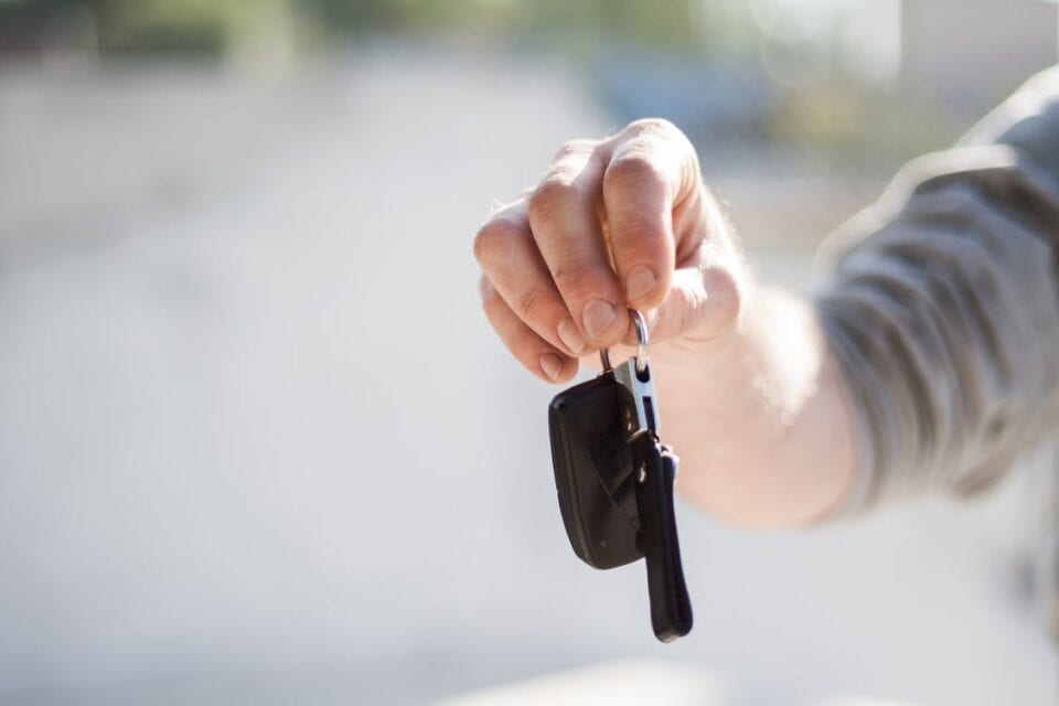 Person handing over rental car keys - rental car insurance coverage concept