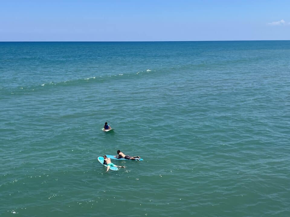 A surfer riding a wave beside the Cocoa Beach Pier in Cocoa Beach, Florida